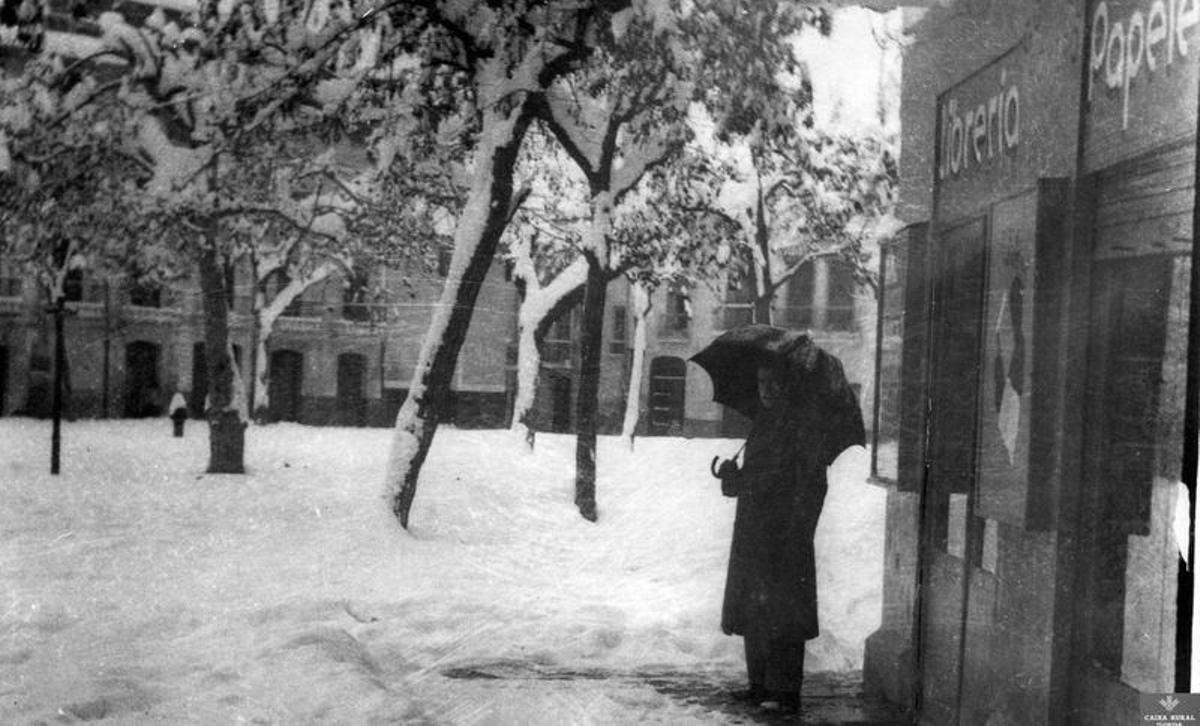 Un hombre se resguarda con un paraguas frente a una librería-papelería en Onda Un hombre se resguarda con un paraguas frente a una librería-papelería en Onda