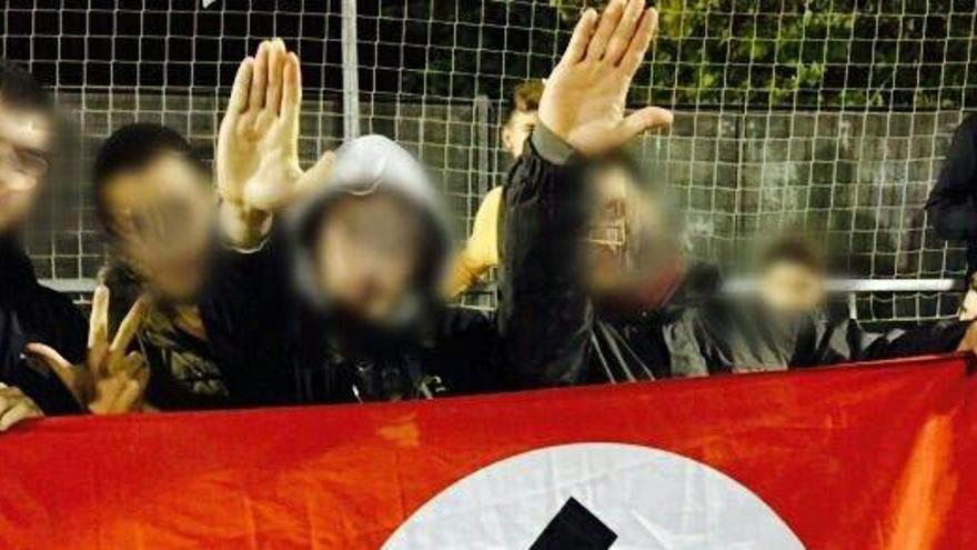 Jóvenes con una bandera nazi en un partido de fútbol, en una fotografía de archivo.