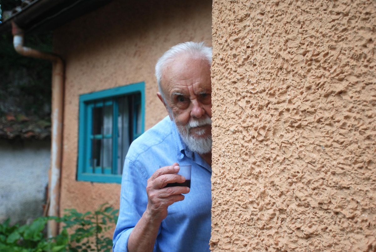 Gonzalo Suárez, este martes, en su casa de Lledías (Llanes), celebrando con humor y un vaso de vino el "Goya de Honor".