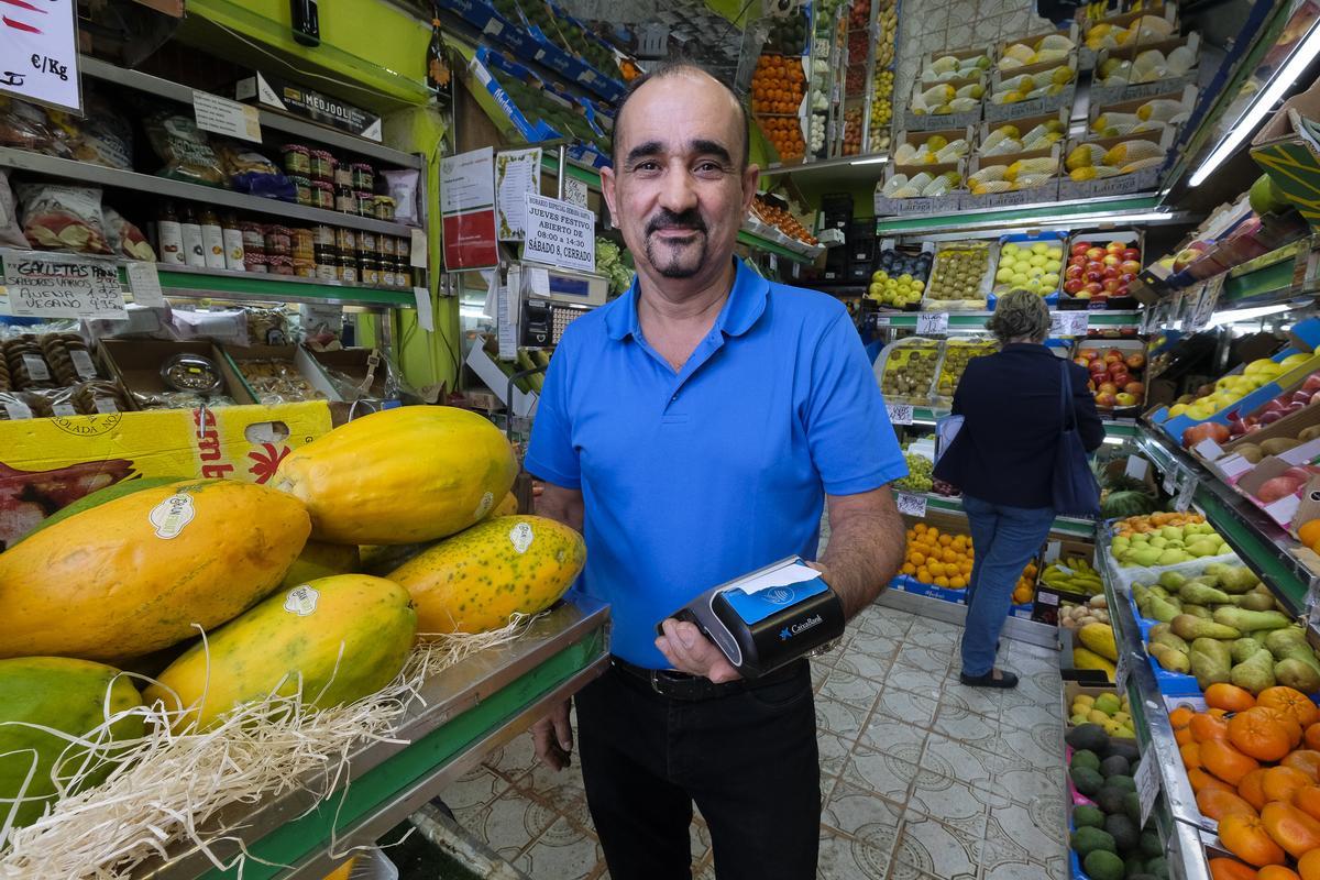Manolo Quintana en su frutería con el datáfono en mano.