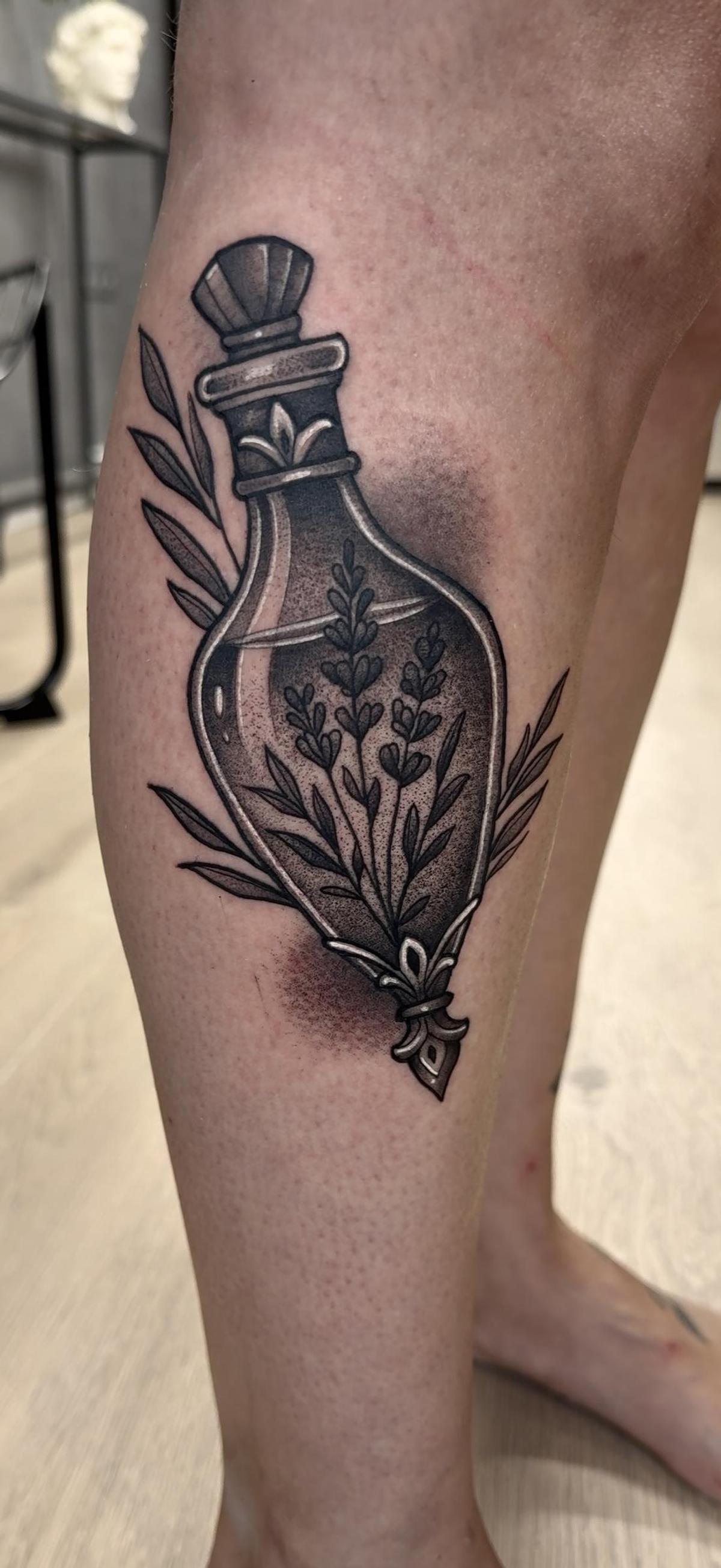 Un frasco de cristal con flores en el interior, uno de los tatuajes realizados en Tattoo Lab.