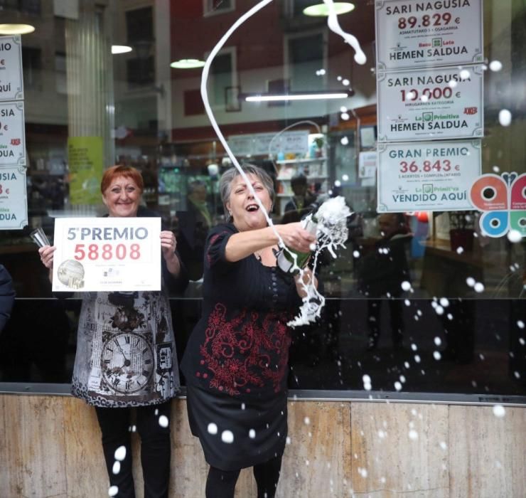 Las loteras María Jesus (d) y Begoña celebran el reparto del quinto premio de la lotería de Navidad, que le ha tocado al número 58808, en un punto de venta de la calle Castaños de la capital vizcaína. EFE