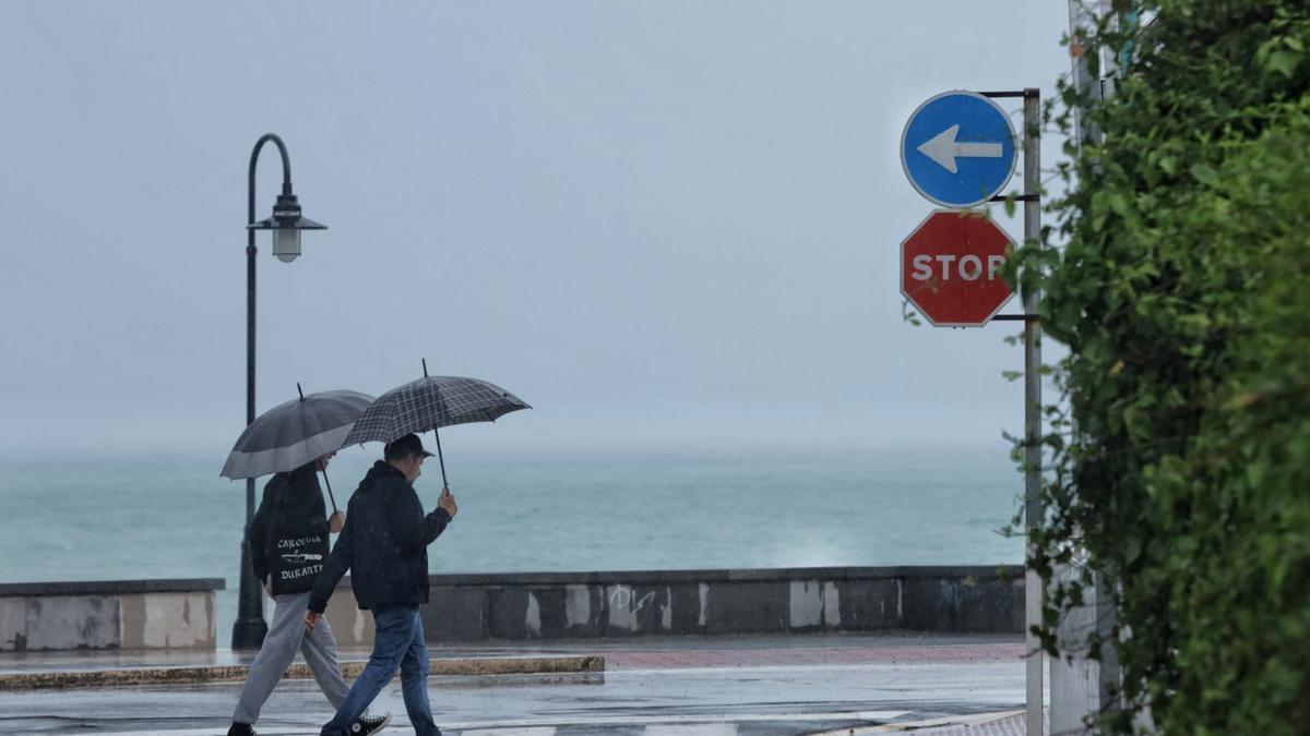 Archivo. Dos viandantes se resguardan de la lluvia en Benicàssim, localidad donde esta tarde se espera más agua.