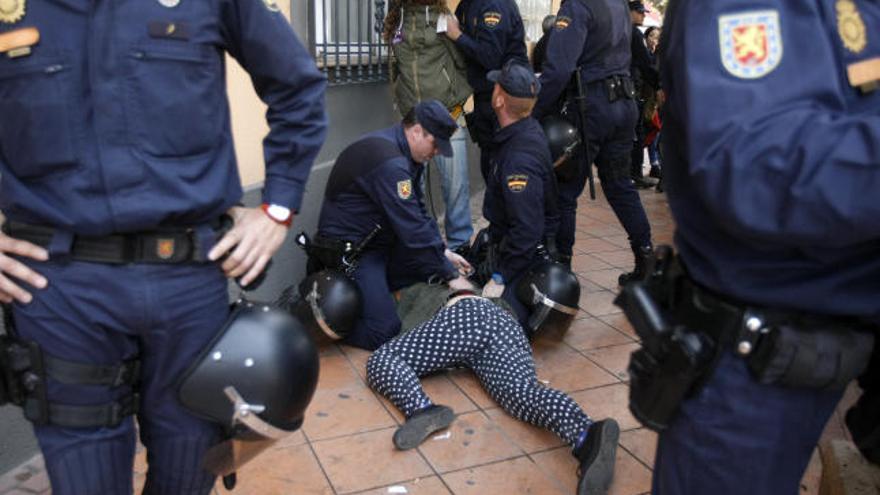 Policías sujetan a Raquel, en el suelo, mientras otro agente pone las esposas a Daniel, al fondo de la imagen.