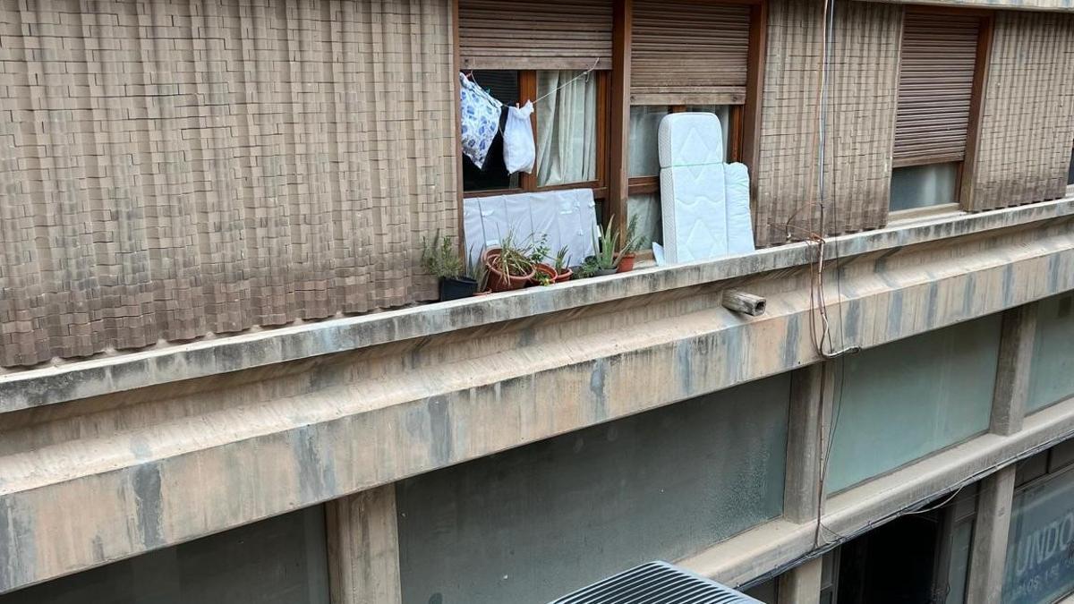 Un colchón y una almohada en el alféizar de una ventana del segundo piso de un edificio de la Travesía Ramón y Cajal.