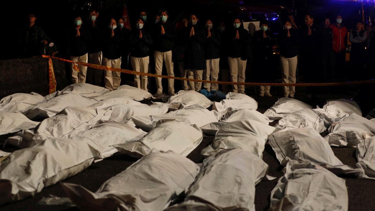 Volunteers pray in front of bodies found in a crashed bus in Taipei