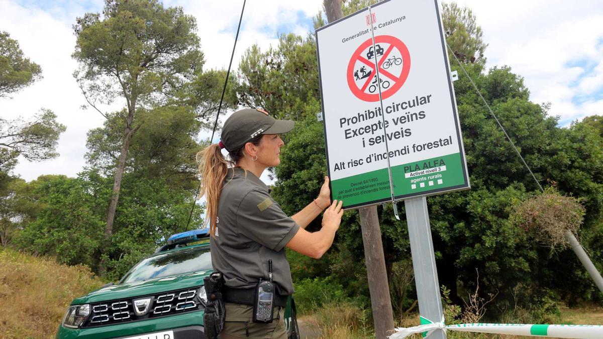 Una agent rural desplegant un cartell que informa sobre el tancament del parc natural del Montgrí, en una imatge d&#039;arxiu