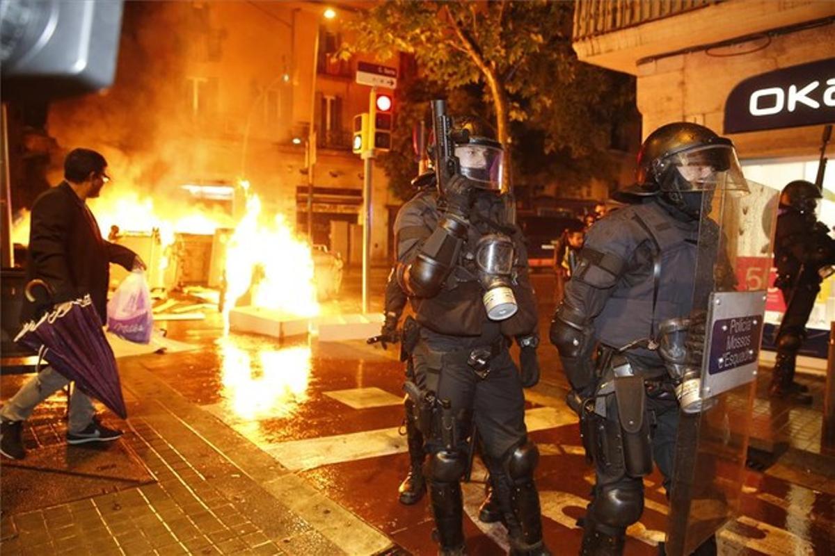 Un grupo de mossos, delante de varios contenedores en llamas en Sants.
