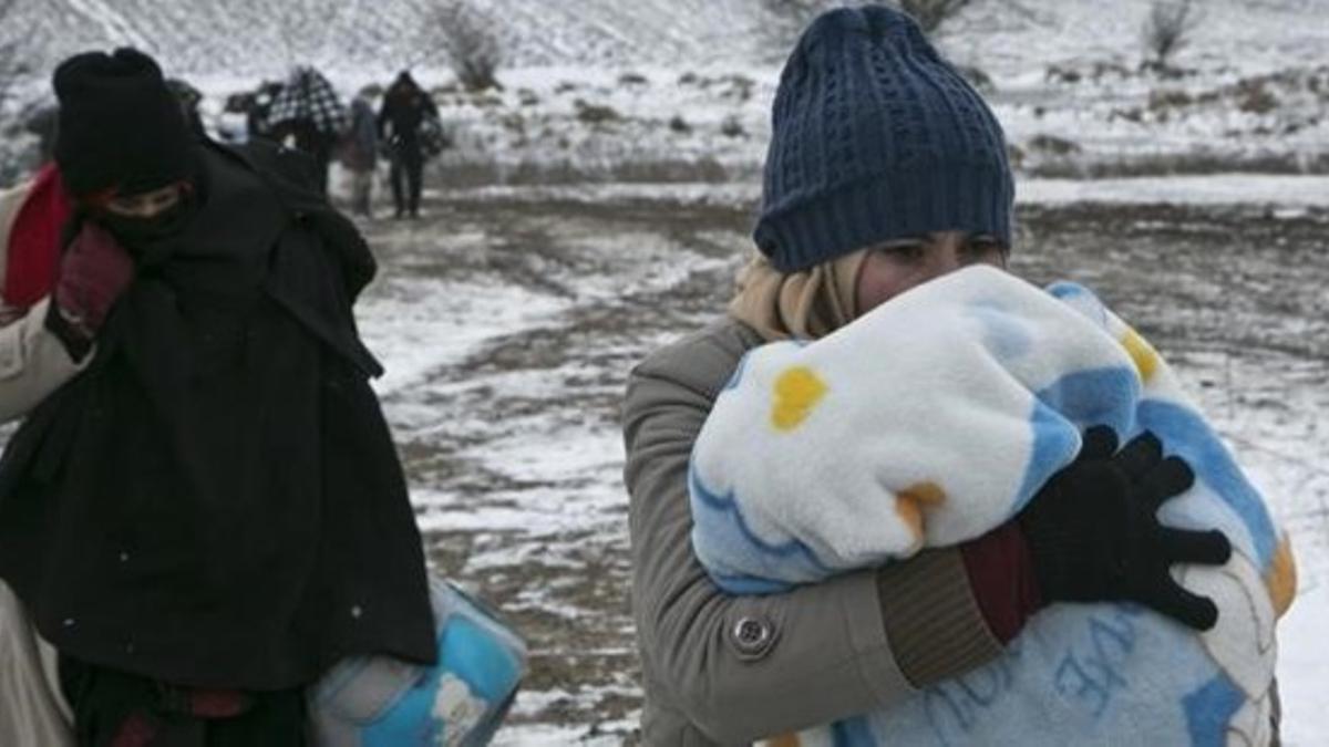 Una mujer migrante protege a su hijo con una manta mientras camina cerca de Miratovac (Serbia), este lunes.