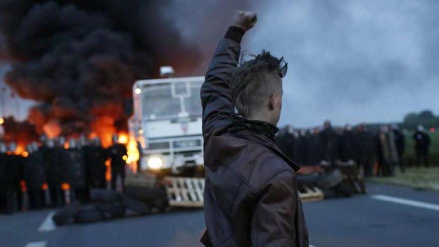 Un manifestante alza el puño ante un grupo de antidisturbios franceses que pretenden romper el bloqueo a una refinería en el nordeste del país.