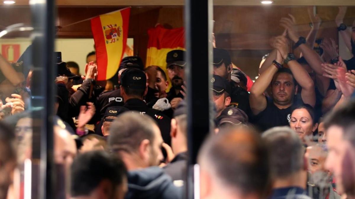 Policías nacionales, en la entrada del hotel de Pineda en el que están alojados, se enfrentan a los ciudadanos que protestan fuera.