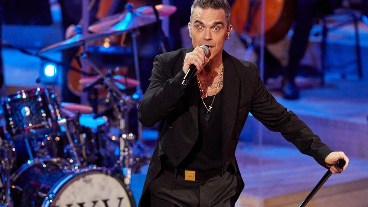 Archivo - 15 November 2022, Hamburg: British singer Robbie Williams and musicians of the New Philharmonic Orchestra Frankfurt perform on stage during a live concert in the Great Hall at the Elbphilharmonie. Williams gave a concert to celebrate 25 years of