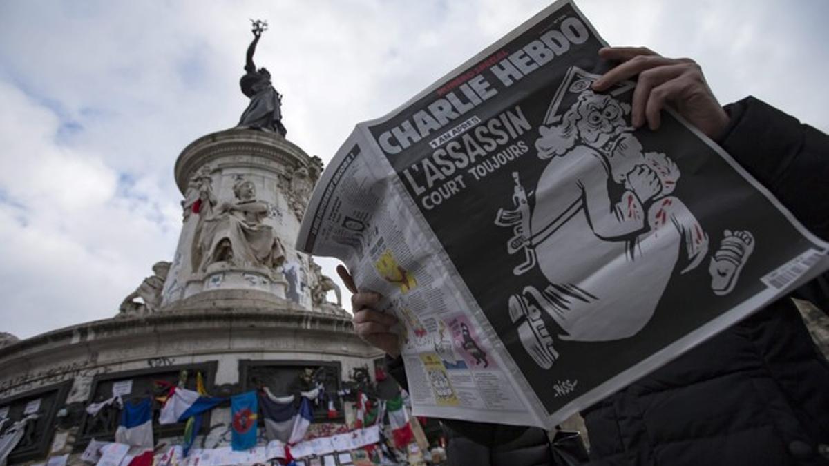 Un lector con el último 'Charlie Hebdo' en la plaza de la República.