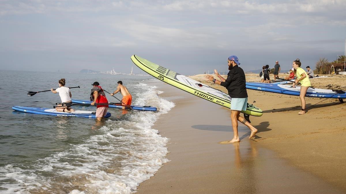 Miembros del Fithouse Training Center se disponen a salir a practicar paddle surf, en la playa de Ocata, El Masnou.