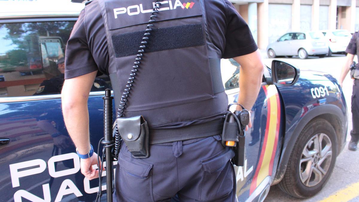 Agente frente a un coche de la Policía Nacional.