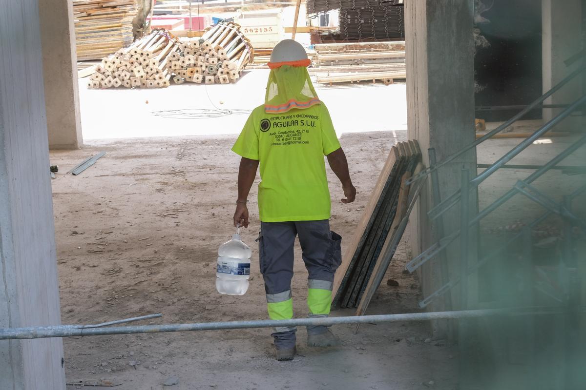 Un operario lleva una garrafa de agua fresca para repartir entre sus compañeros e hidratarse ante la ola de calor