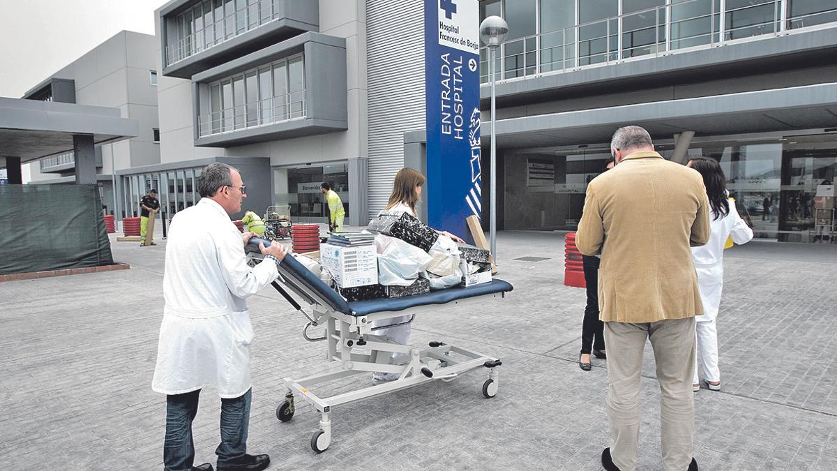 Un sanitario traslada enseres del viejo al nuevo hospital utilizando una camilla como carro