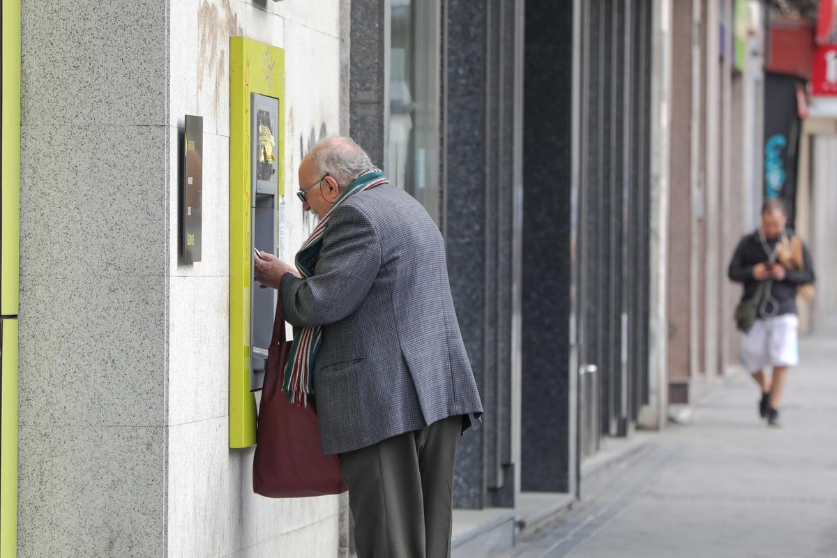 Archivo - Un anciano saca dinero de un cajero, en una imagen de archivo Archivo - Un anciano saca dinero de un cajero, en una imagen de archivo