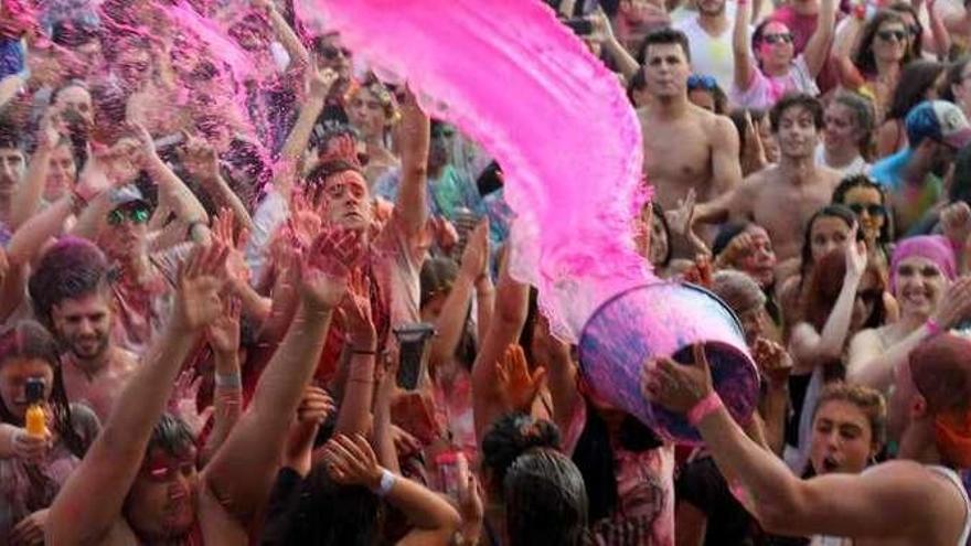 Numerosos asistentes bailan mientras una persona arroja un cubo con pintura ecológica, ayer, en Playa América. // D.P.