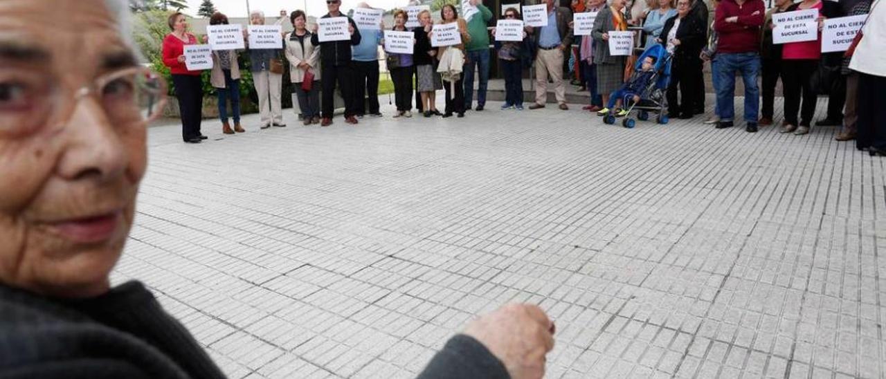 La concentración vecinal organizada ayer delante de la oficina de Liberbank que cierra sus puertas.