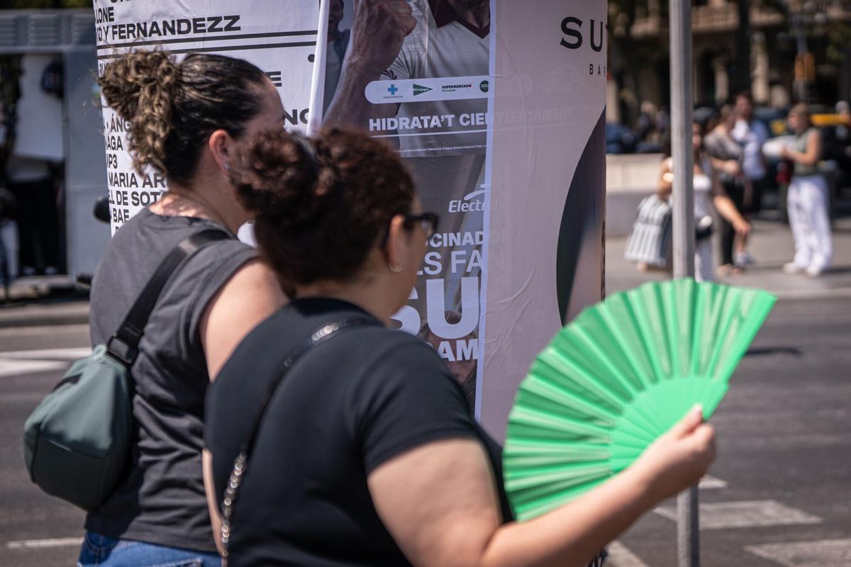 Personas abanicándose por las altas temperaturas en Barcelona.