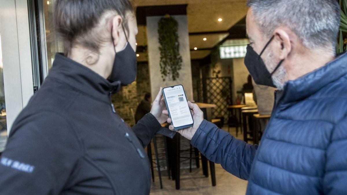 Un cliente muestra su pasaporte covid antes de entrar en un establecimiento de Alicante. | PILAR CORTÉS