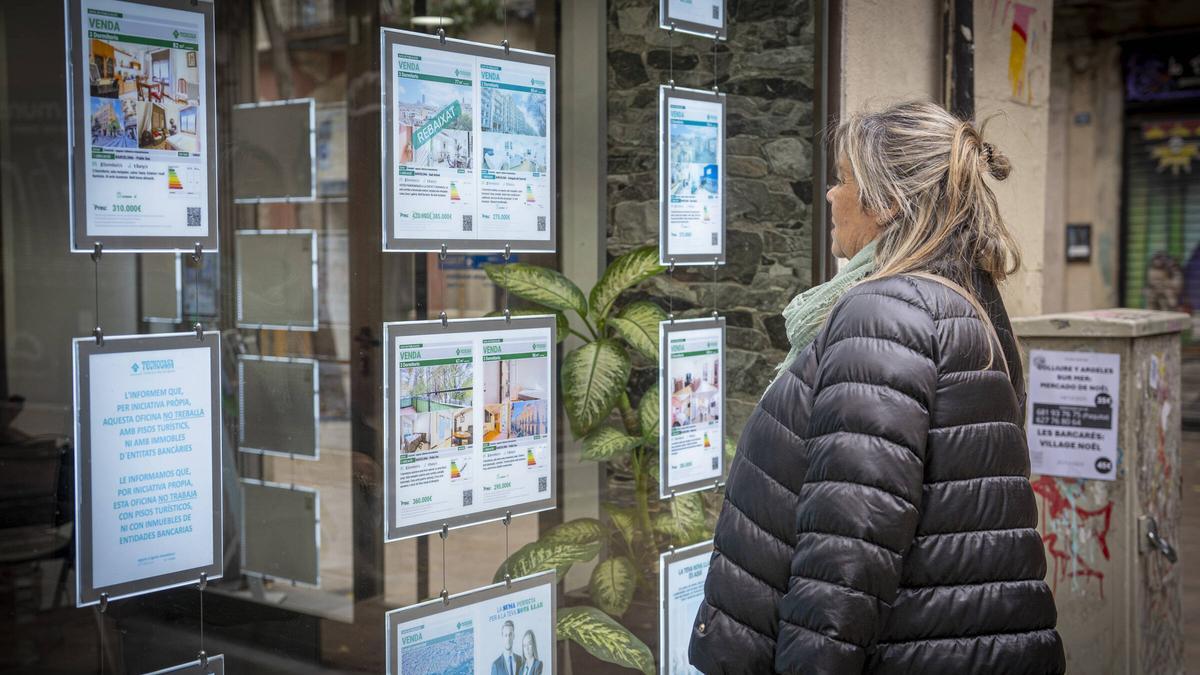 Una mujer consulta los anuncios de una inmobiliaria en Barcelona