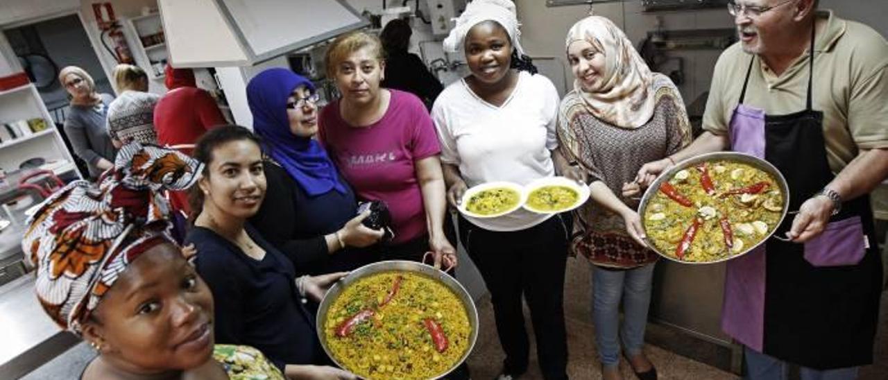 Algunas de las participantes del curso mostrando platos típicos mediterráneos, una fideuà, una paella y arroz caldoso