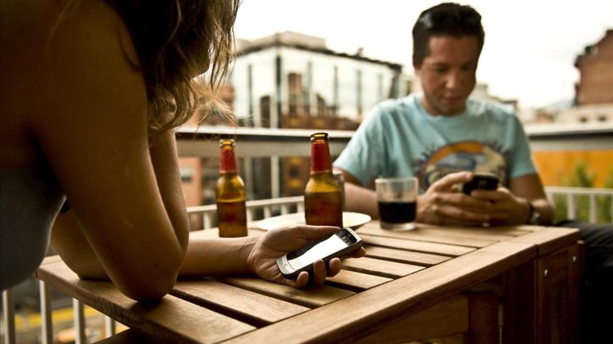 Una pareja de turistas consulta sus móviles en una terraza de Barcelona.