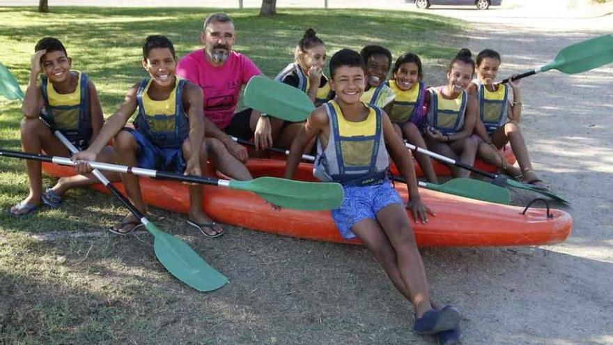 El grupo de niños saharauis posan con las piraguas junto a José, uno de los monitores.