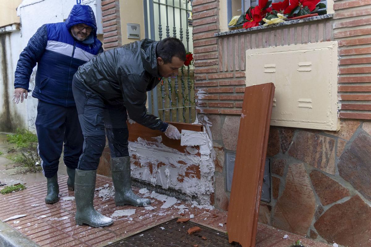 Un vecino de la barriada de Santa Ana sella con el palustre el acceso al interior de su vivienda ante la crecida del río Guadalhorce