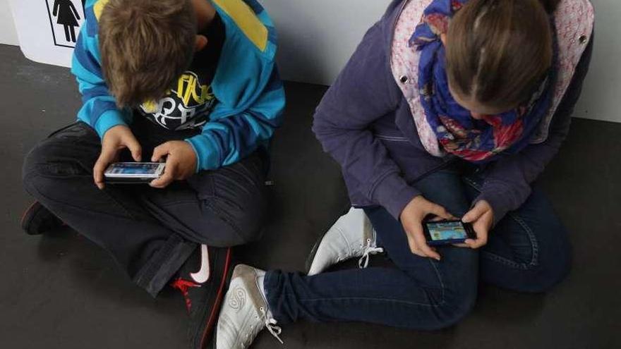 Dos niños juegan con sendos teléfonos móviles.