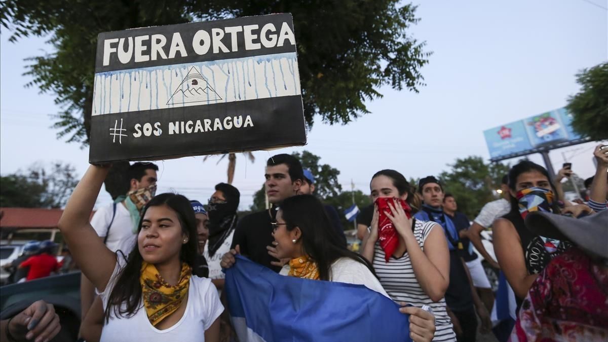 mbenach43042938 a woman holds a sign that reads in spanish  ortega out   dur180423194905
