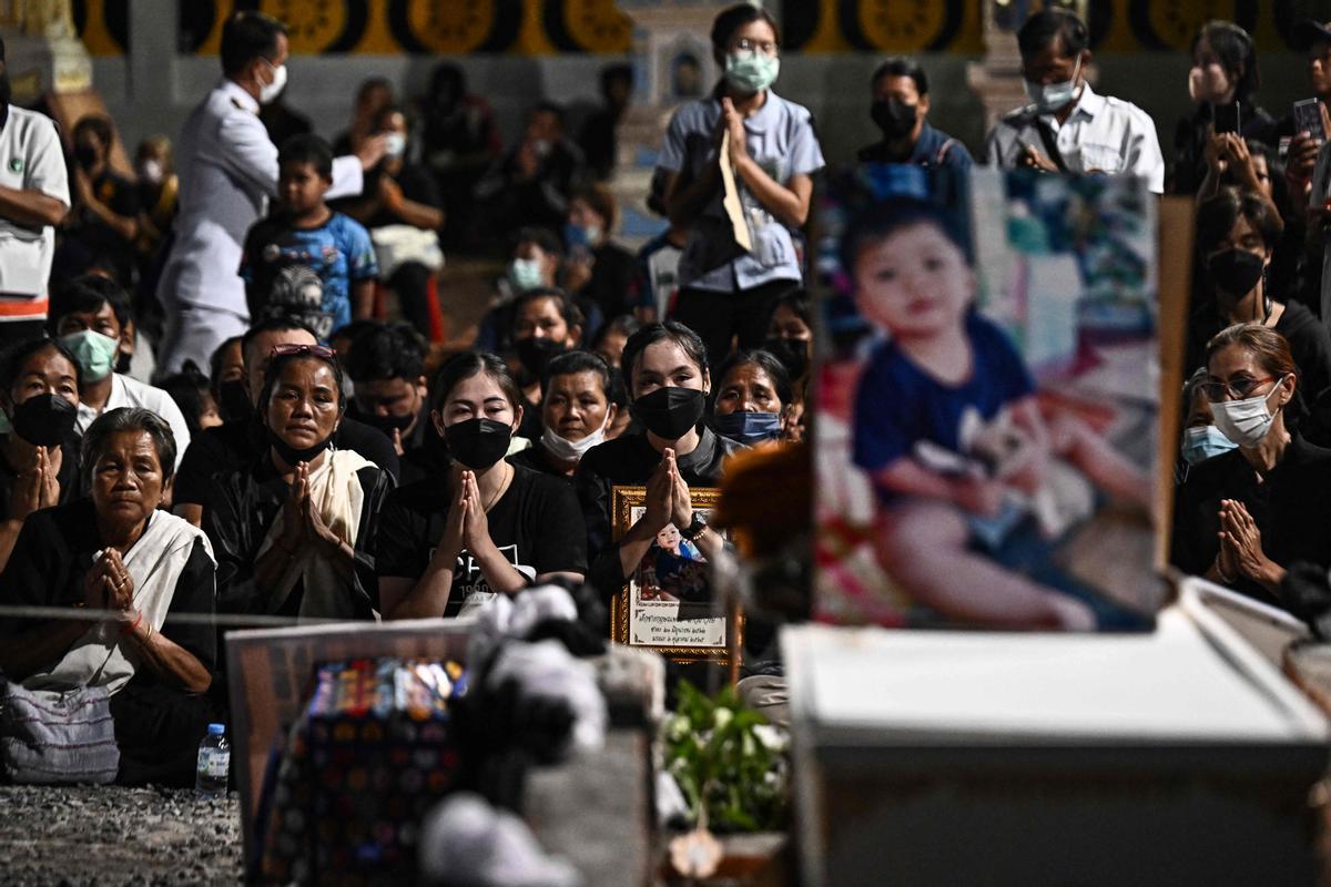 La gente observa cómo las piras funerarias incineran a 19 víctimas del tiroteo en la guardería de Uthai Suwan en el templo Wat Rat Samakee en Uthai Sawan. Un exoficial de policía disparó y mató a 37 personas, al menos 24 de ellos niños, después de irrumpir en una guardería infantil en el noreste de Tailandia.