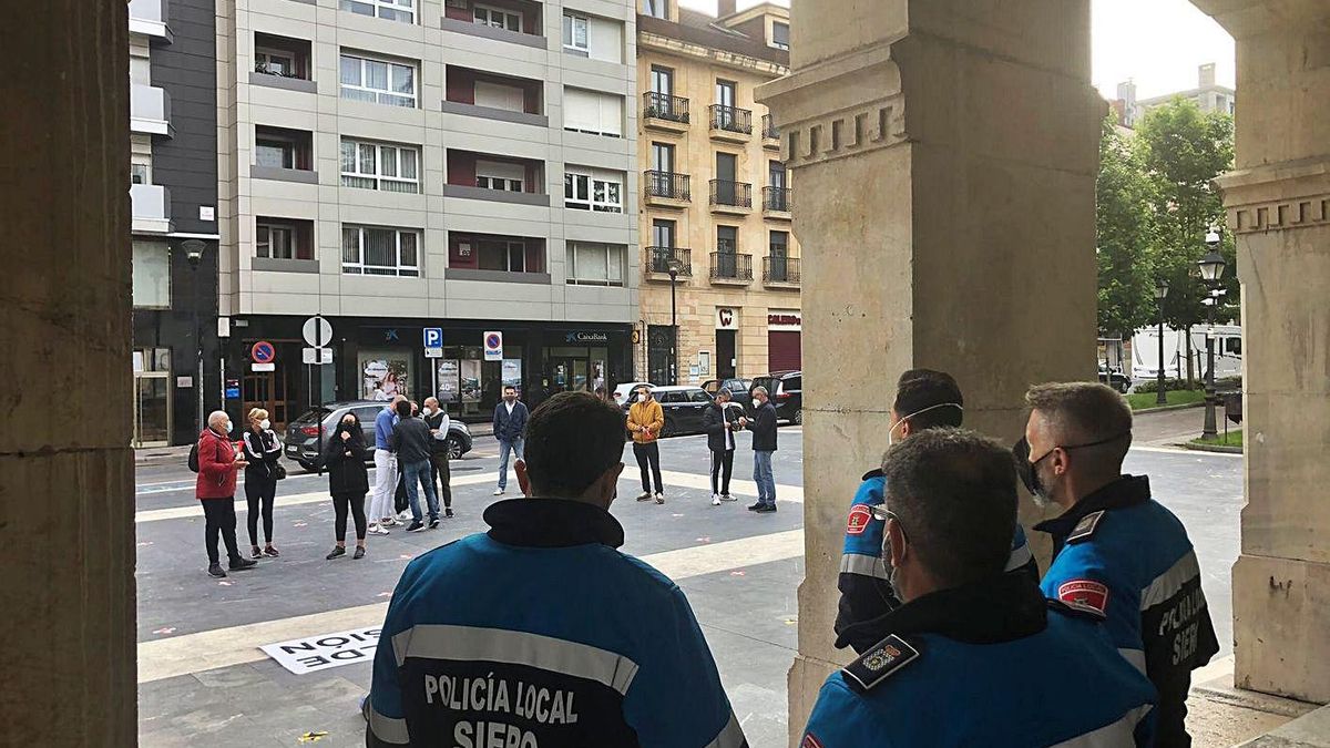 Agentes de Policía, de espaldas, ayer, en los soportales del Ayuntamiento. En la plaza, al fondo, los manifestantes.