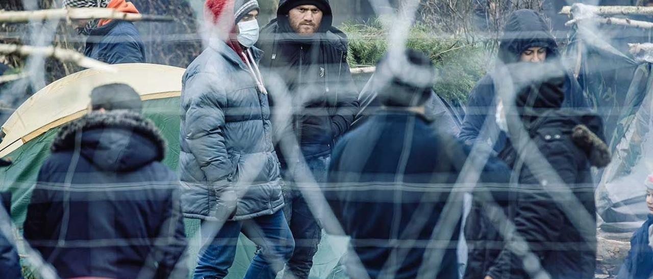 Migrantes tras la valla fronteriza en Bielorrusia, cerca del paso fronterizo de Kuznica, entre Polonia y Bielorrusia