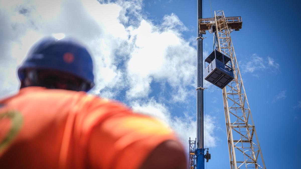 Un operario observa el izado de una caseta de obra durante su jornada laboral.