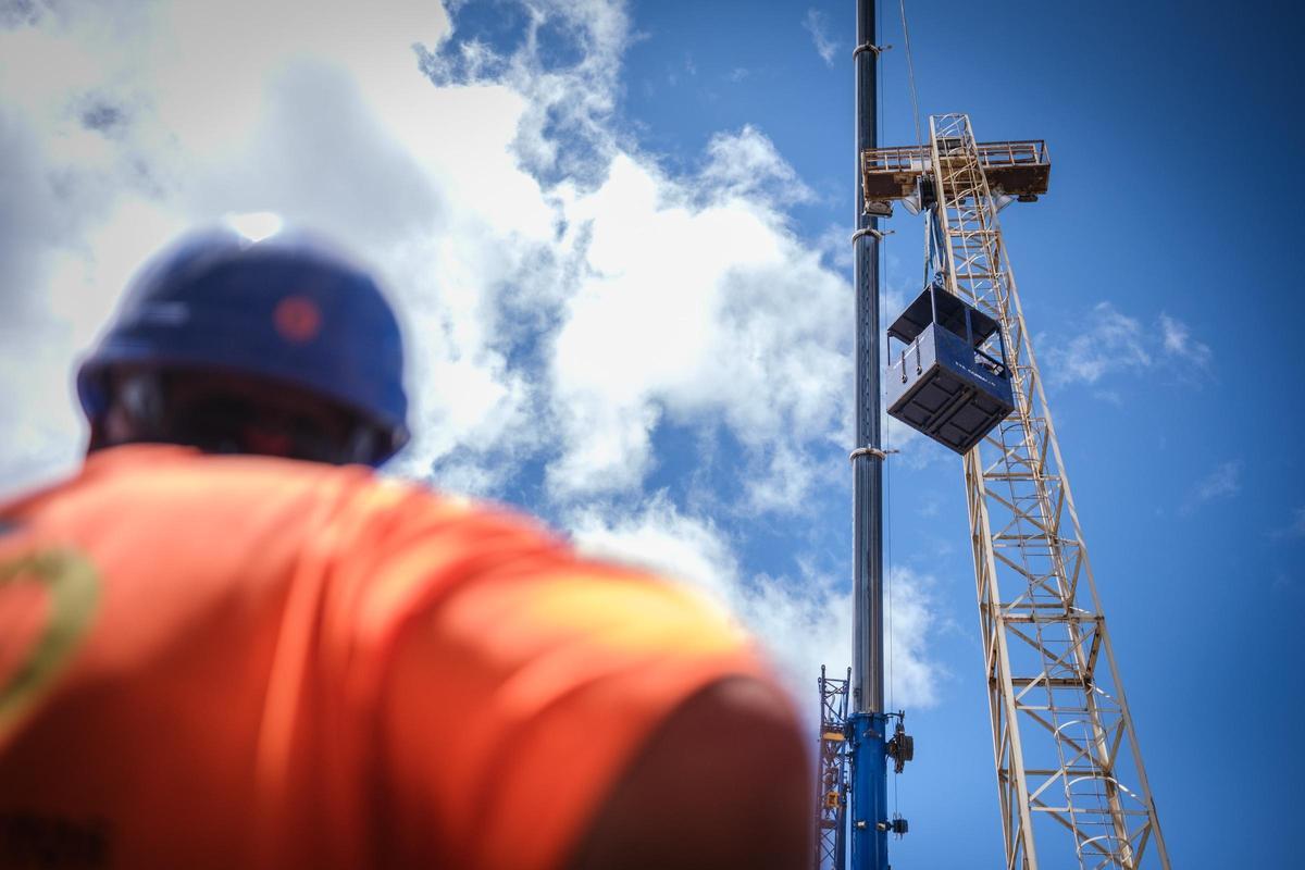 Un operario observa el izado de una caseta de obra durante su jornada laboral.
