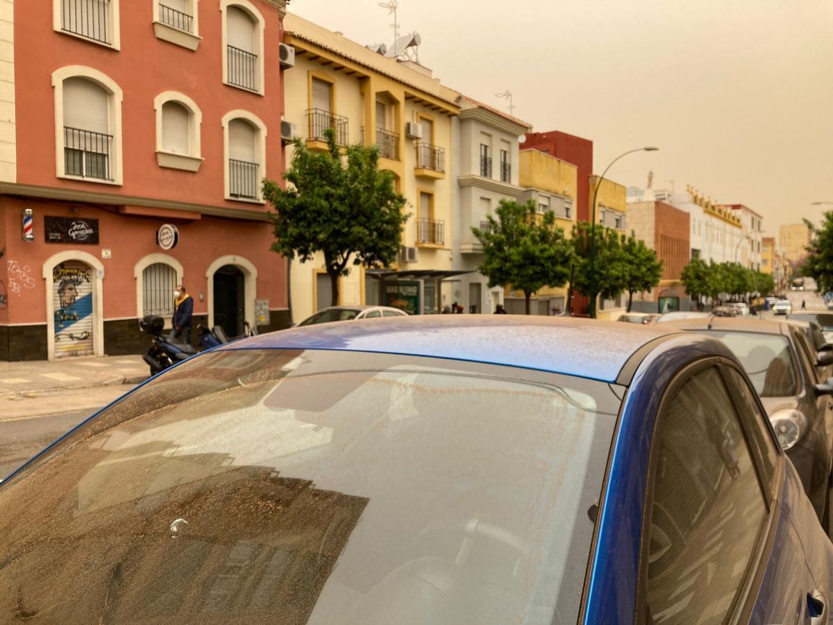 El parabrisas de un coche aparcado en la calle lleno de barro y el cielo naranja en la mañana de esta martes en el barrio de Capuchinos.