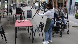 Una mujer organiza la terraza del bar en el que trabaja, en la rambla del Poblenou.