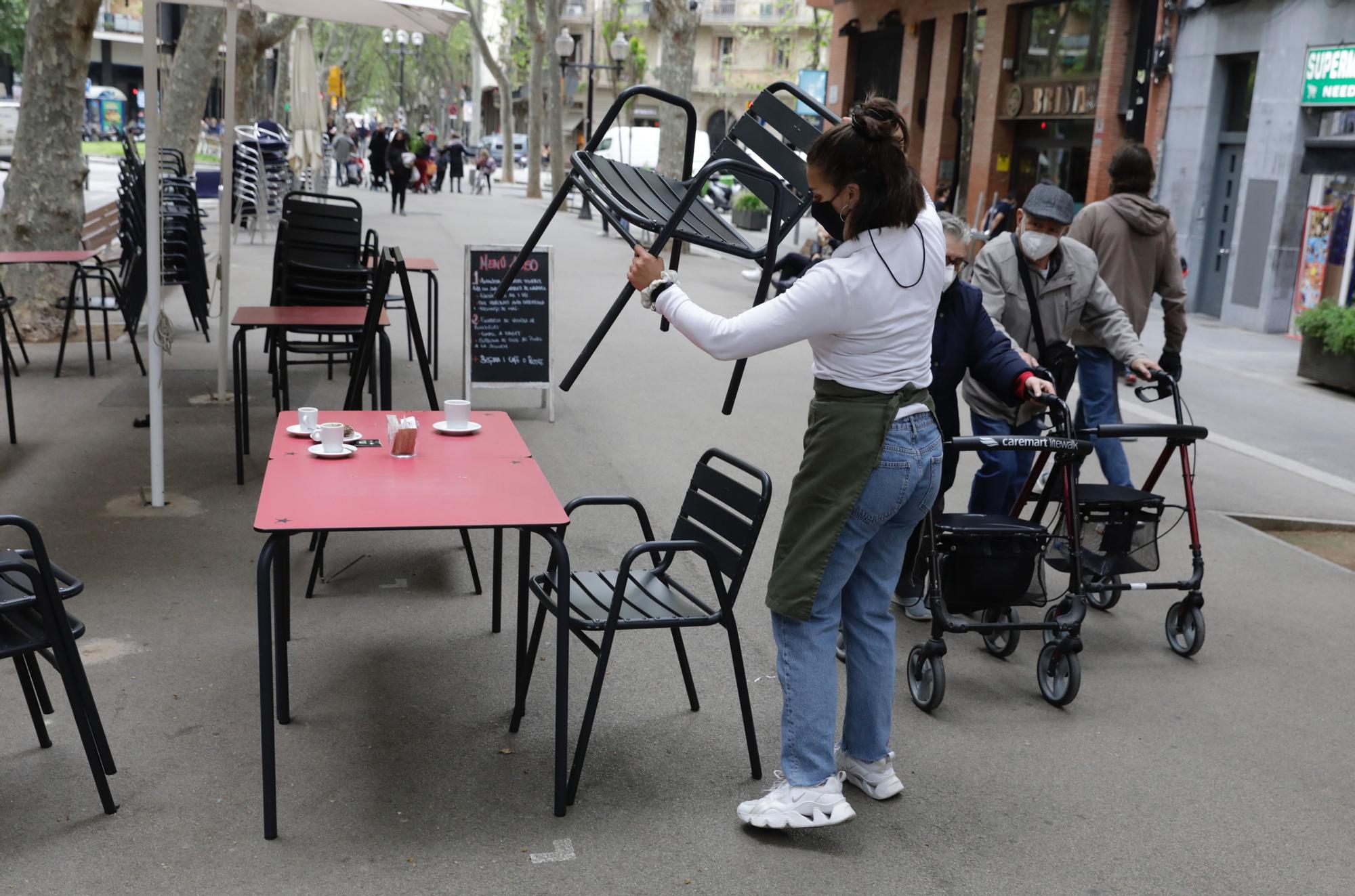 Una mujer organiza la terraza del bar en el que trabaja, en la rambla del Poblenou.