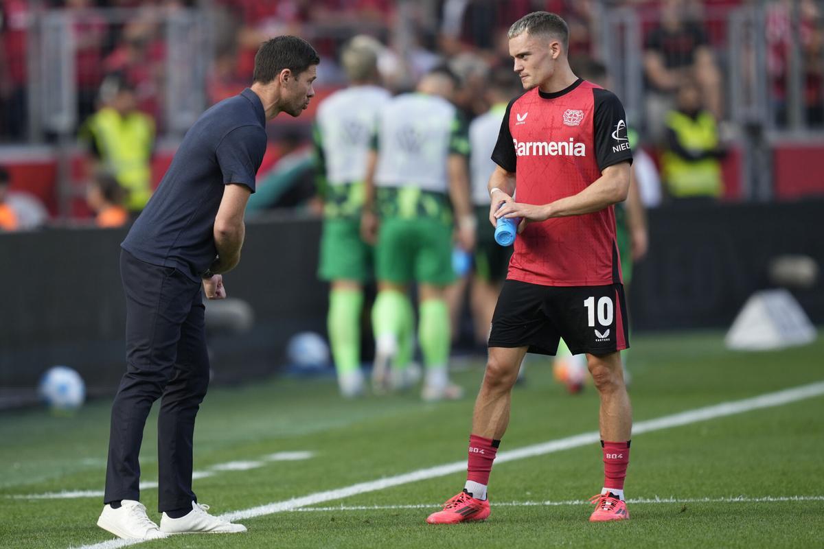 Leverkusen's head coach Xabi Alonso talks to his player Florian Wirtz during the German Bundesliga soccer match between Bayer Leverkusen and VfL Wolfsburg at the BayArena in Leverkusen, Germany, Sunday, Sept. 22, 2024. (AP Photo/Martin Meissner)