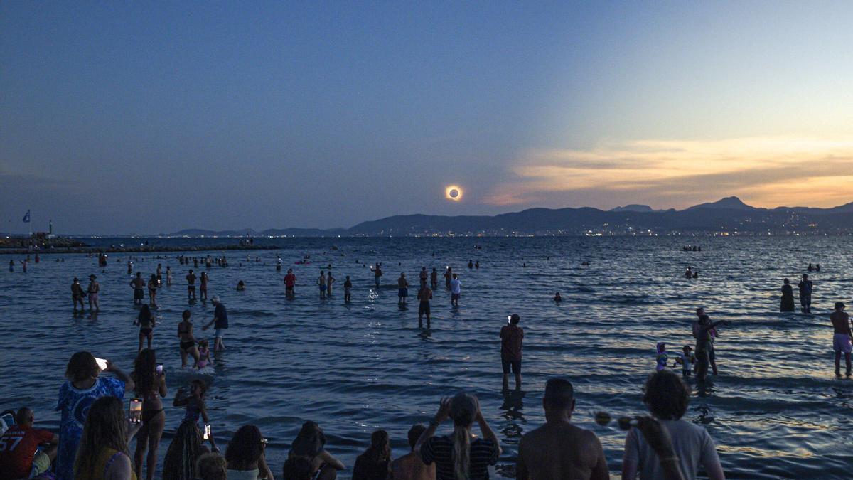 Unas 60.000 personas enmudecen mirando al cielo ante el eclipse en la Playa de Palma