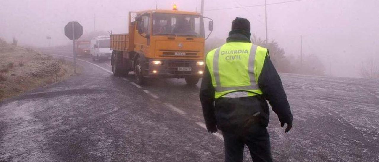 Un guardia civil supervisa el tráfico en una carretera afectada por las heladas. // FdV