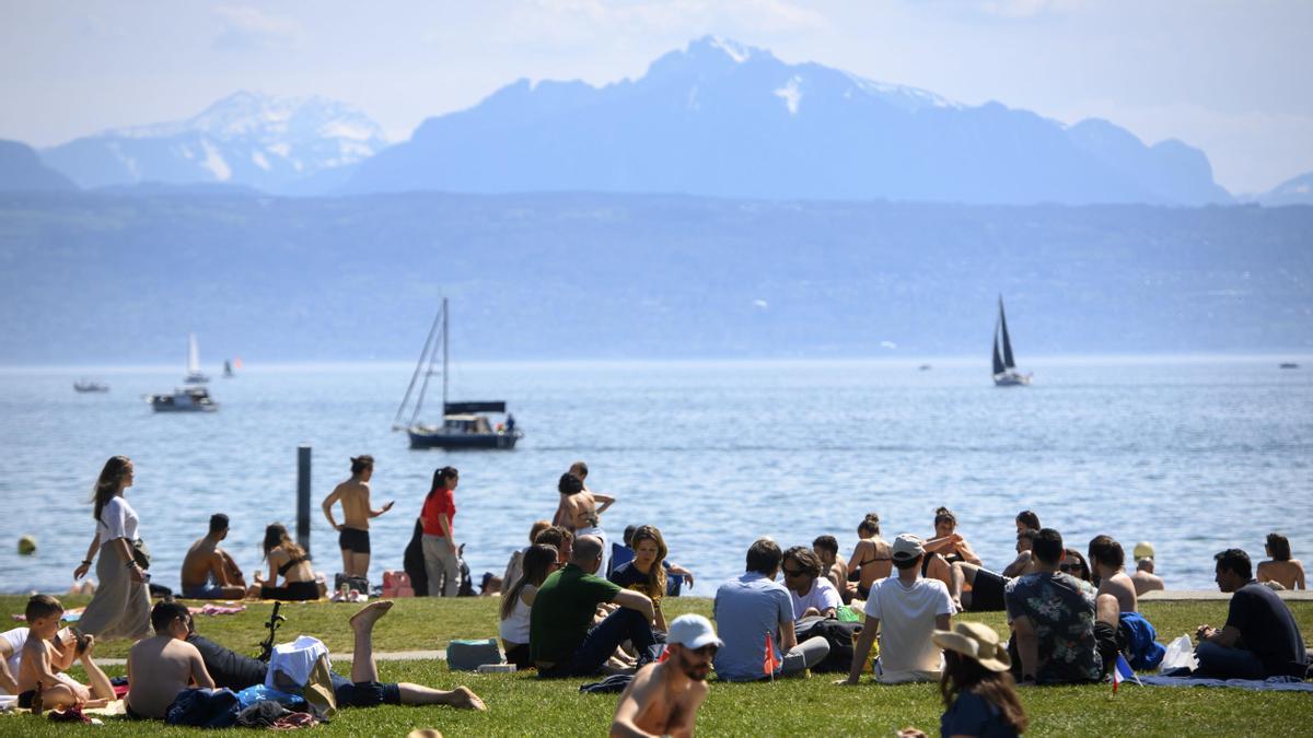 Varias personas disfrutan del buen tiempo junto al lago de Ginebra.