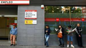 Diversos ciutadans esperen que obri una oficina d’ocupació de Madrid, l’abril passat.