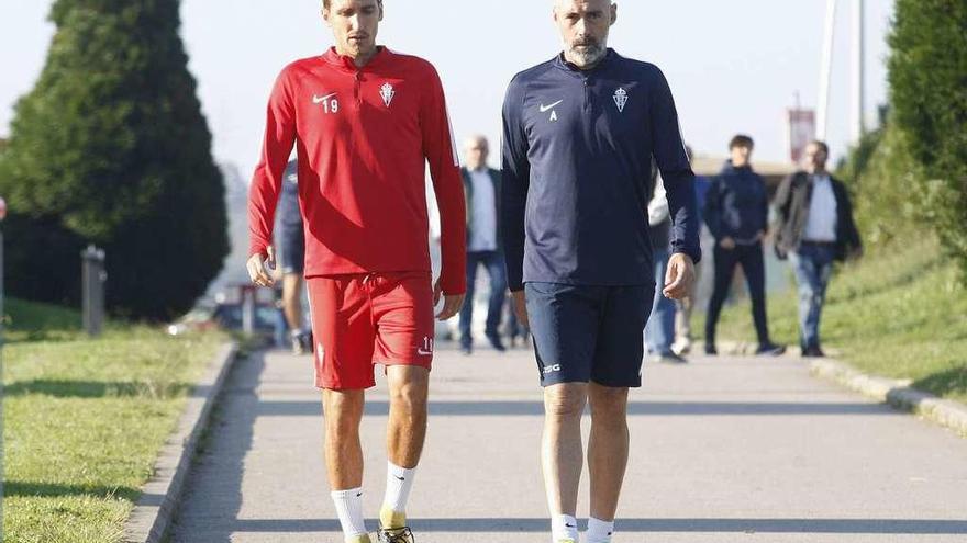 Scepovic camina junto a Ángel Rodríguez, segundo entrenador del Sporting, durante un entrenamiento.
