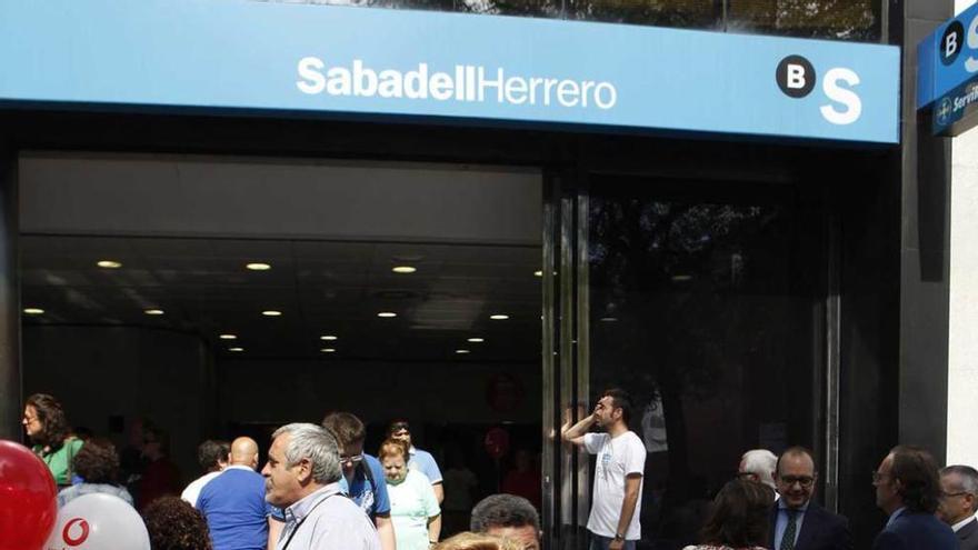 A la izquierda, foto de familia de las autoridades en el Día del Banco Sabadell Herrero; a la derecha, asistentes abandonan el stand de la entidad con bolsas de regalo.
