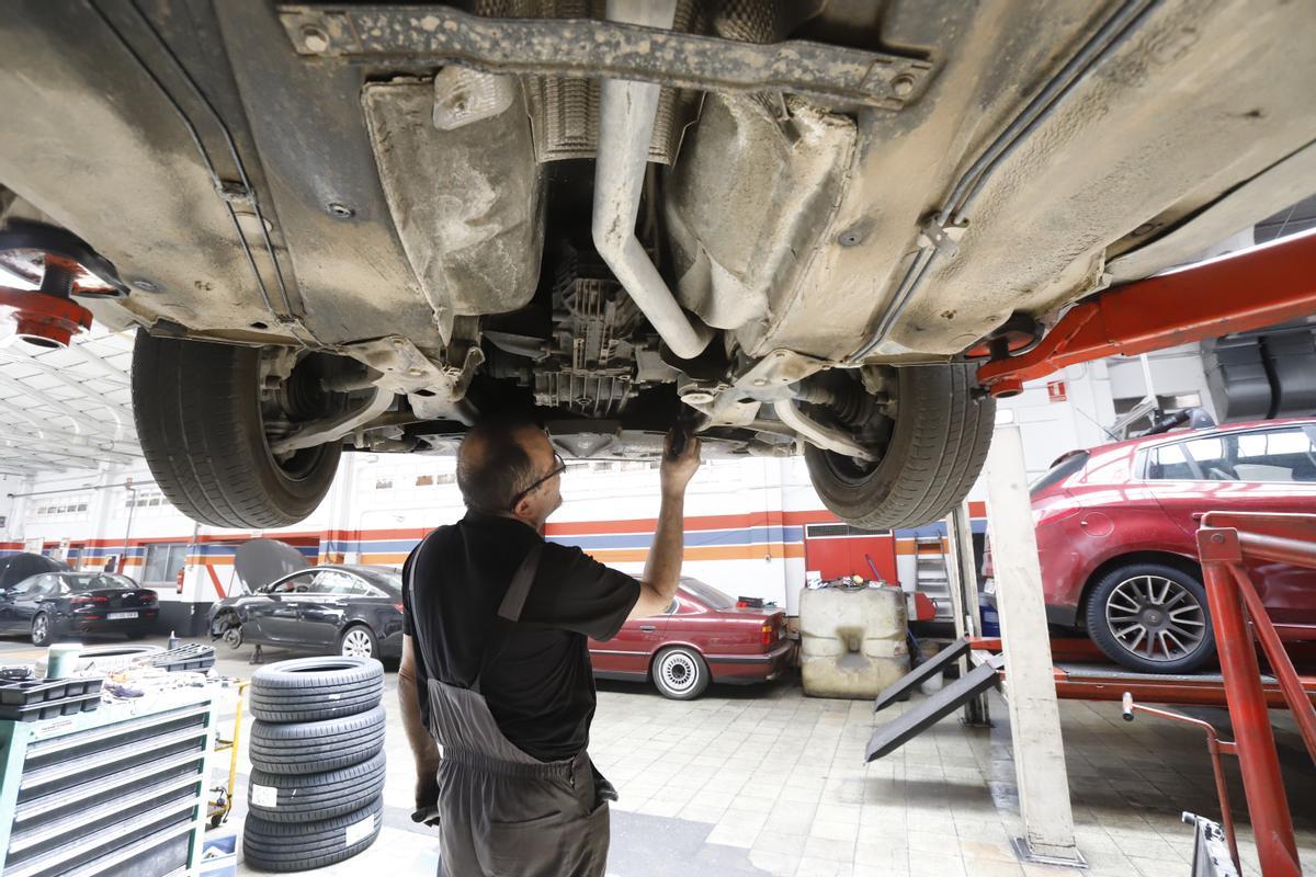 Un mecánico supervisa los bajos de un coche en un taller de Zaragoza.
