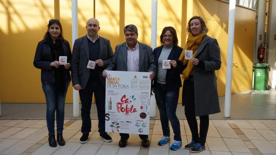 Las autoridades sostienen el cartel con la nueva marca social de sa Pobla.